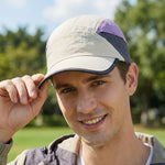 Venzina Sun Cap worn by man outdoors adjusting brim showing beige, purple, and gray panel design