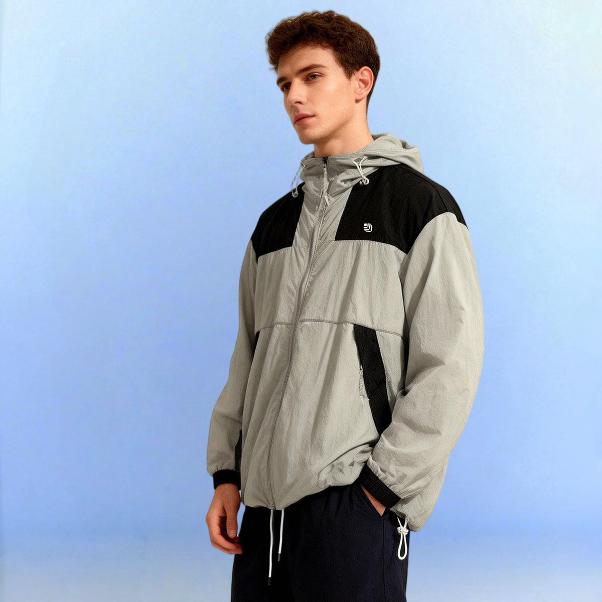 Venzina Sunscreen Jacket for Men worn, 3/4 side view, grey-black color-block hoodie with drawcord hem, studio blue backdrop