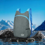 Venzina waterproof foldable backpack in grey on rock by water, outdoor hiking daypack