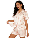 Woman wearing a pink satin pajama set with fruit pattern on a white background