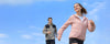 Man and woman wearing lightweight UPF 50+ sun protection jackets running outdoors