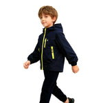 Boy wearing navy blue Venzina waterproof hooded windbreaker jacket with yellow zippers, walking confidently on white background