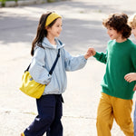 Girl wearing Venzina kids outdoor jacket walking with a friend outdoors — light blue windbreaker jacket styled for school and playtime.