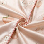 Close-up of pink fabric with cartoonish peach designs and button details