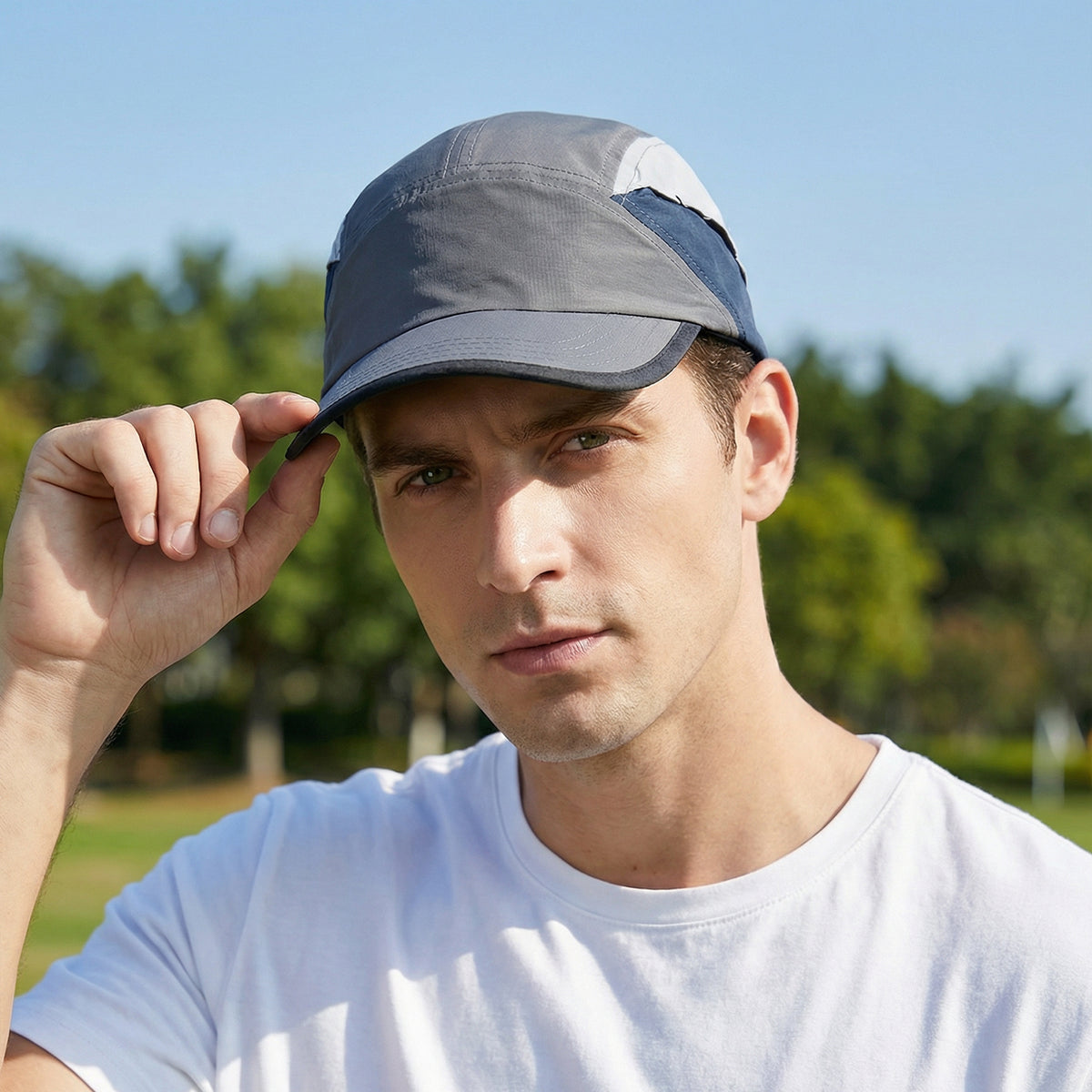 Venzina Lightweight Cap worn by man outdoors adjusting brim with gray breathable panel design