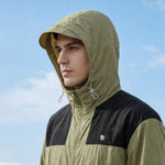 Venzina sun protection jacket close-up profile, olive hood with visor brim and zipper guard, outdoor sky backdrop