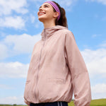 Venzina sun protection jacket women worn outdoors, light pink hooded jacket shown from side view against blue sky during active wear