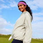 Venzina sun protection jacket women worn side view outdoors, light beige hooded jacket styled with athletic wear under blue sky