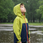 Venzina boy wearing waterproof yellow and navy hooded rain jacket in the rain