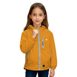Girl wearing mustard orange Venzina waterproof hooded windbreaker jacket with blue zipper, standing against white background