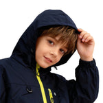Boy wearing navy blue Venzina waterproof hooded windbreaker jacket with yellow zipper, touching hood on white background