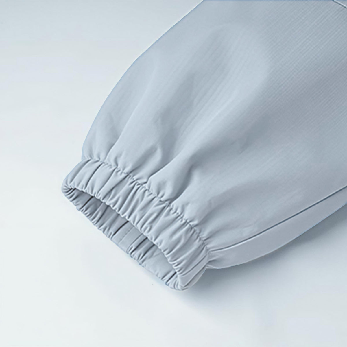 Close-up of light blue kids outdoor jacket sleeve — elastic cuff detail showing windproof design and breathable windbreaker fabric.